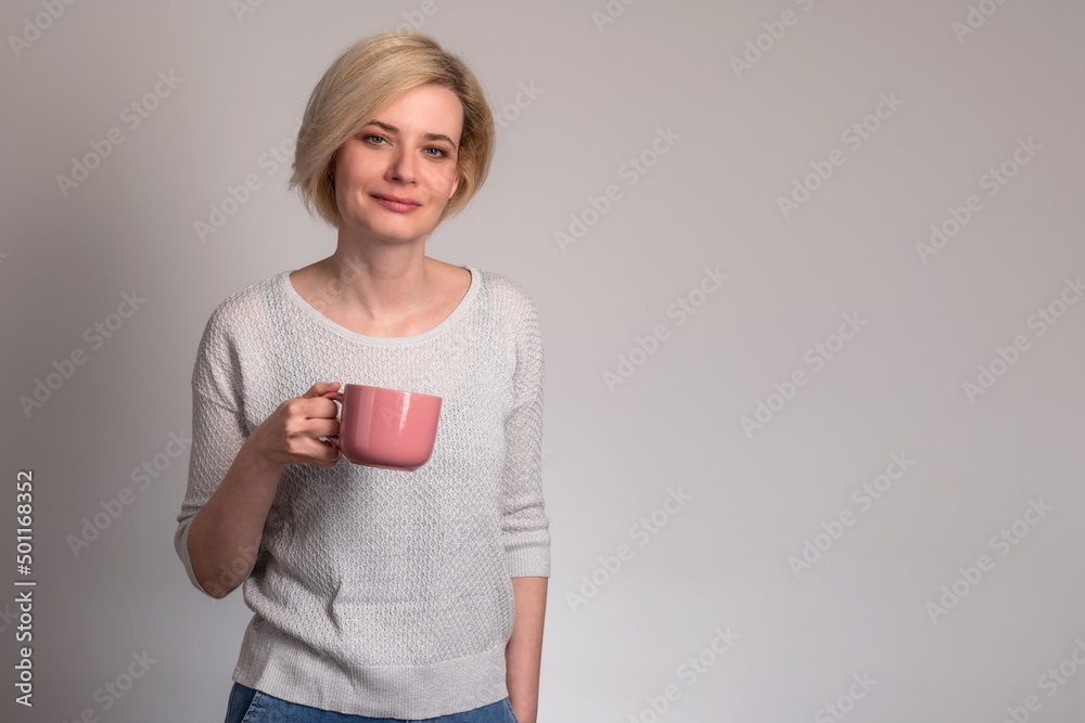 Young cheerful woman with happy smile holding a cup of coffee