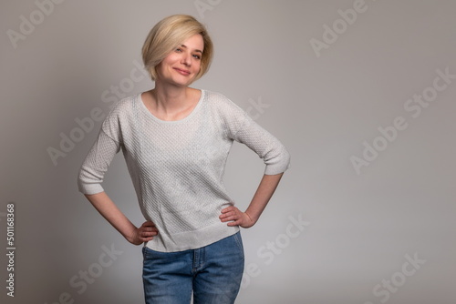 Obraz na płótnie Smiling confidence. Beautiful young blonde women looking at camera and posing while standing against grey background w salonie