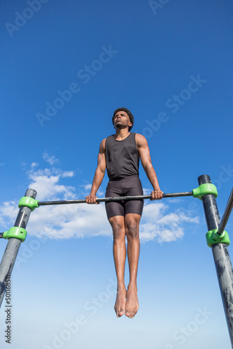 Young guy doing calisthenics. Sporty guy in a calisthenics park. Outdoor training.
