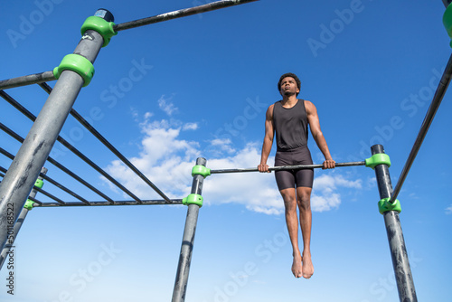Young guy doing calisthenics. Sporty guy in a calisthenics park. Outdoor training.