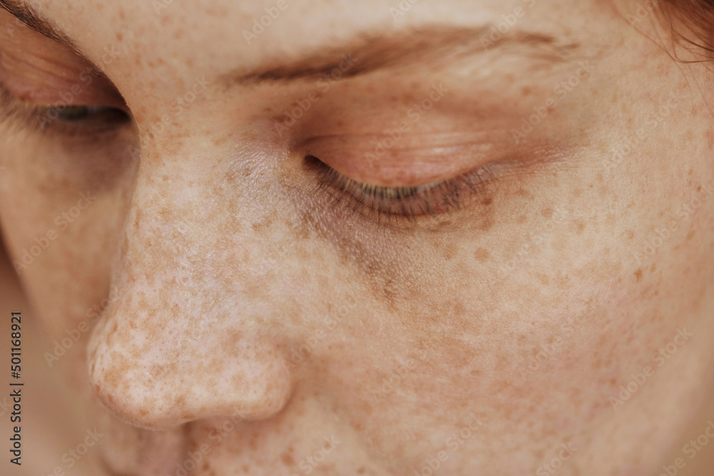 Obraz premium Macro shot of face with freckles of young natural woman with no-makeup on her eyes