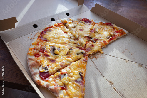 An almost half eaten takeaway pizza in a cardboard box
