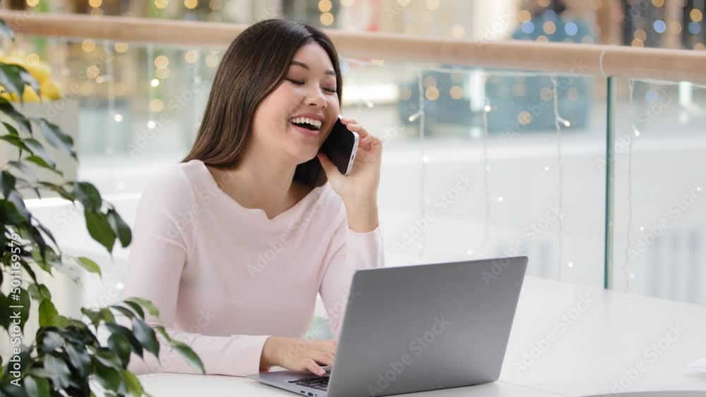 Happy Asian Korean woman freelancer student businesswoman holding mobile phone call working with laptop multitasking girl making online order communicating with friend distant friendly carefree talk Happy Asian Korean woman freelancer student businesswoman holding mobile phone call working with laptop multitasking girl making online order communicating with friend distant friendly carefree talk