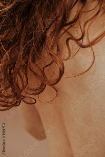 Rear view of young shirtless woman with long red curly hair photo