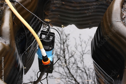 Obraz na płótnie Pumping dirty water and sludge with a pump from a garden plastic reservoir in sp