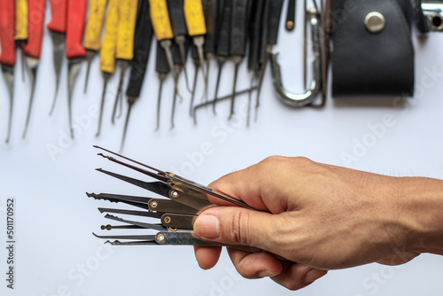 Many key picks in locksmith's hand are tools that require skill and practice to work in picking or unlocking locked key with an available key picker.concept of practice using locksmith tools to unlock photo