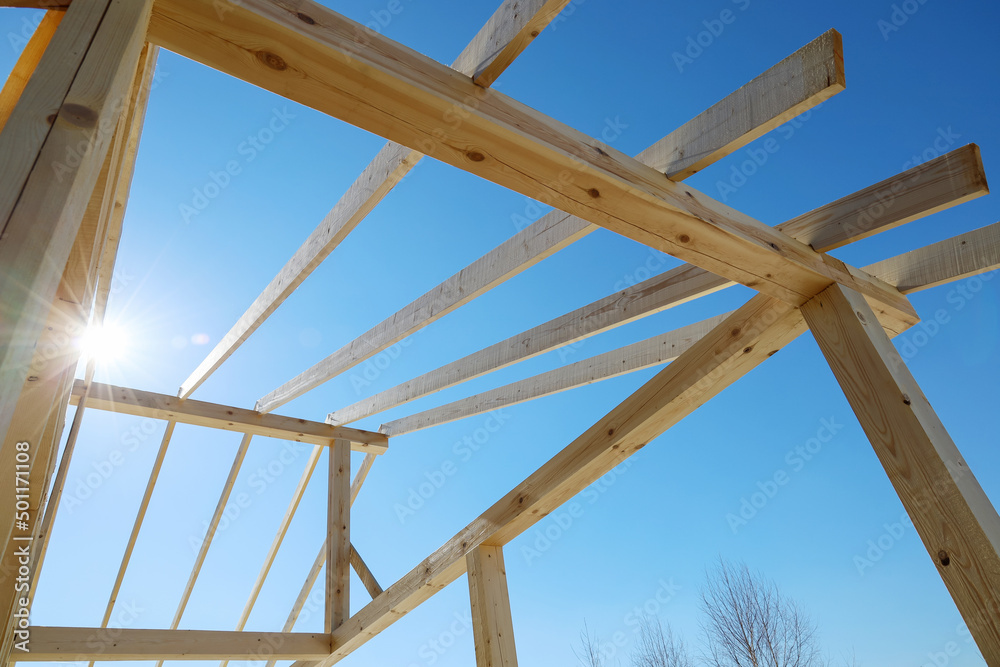 Obraz premium Supporting wooden structure for roof rafters, repeating beams on background of sky