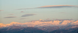 Lenticular clouds over snowy mountains at sunset