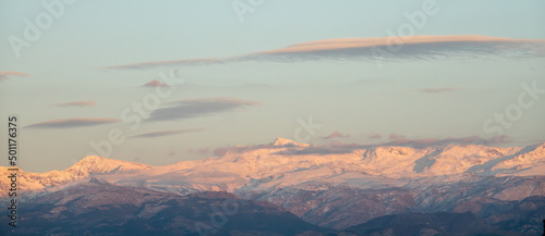 Lenticular clouds over snowy mountains at sunset