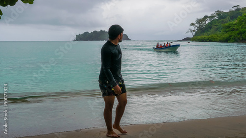 Joven adulto caminando en la playa en un día nublado 