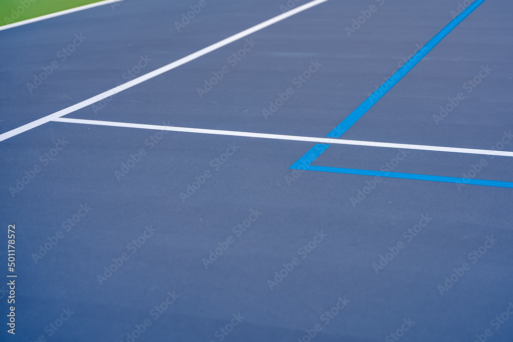 Blue tennis court with white lines and light blue pickleball lines.	