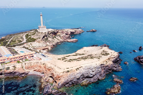 Bird's eye view of a beautiful lighthouse standing on the rocky coast of Spain near the sea.