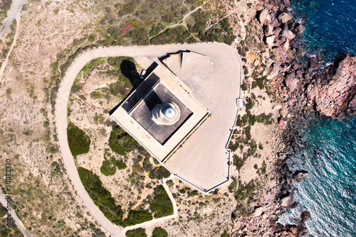 Bird's eye view of a beautiful lighthouse standing on the rocky coast of Spain near the sea.