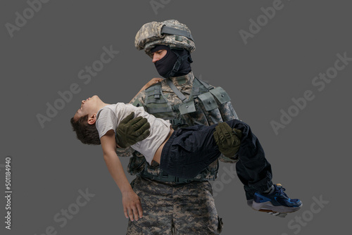 Shot of serviceman dressed in camouflage uniform rescuing little injured boy.