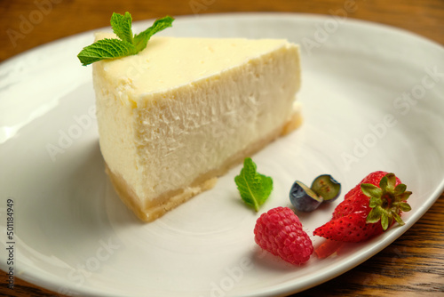 A piece of cheesecake, a classic New York-style cheesecake on a wooden table