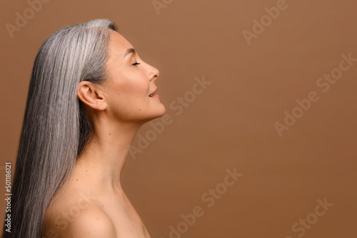 Obraz na plátně Side view at sensual naked middle-aged beautiful Asian woman with long grey hair, her eyes closed, body and face care concept