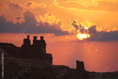 The famous "Wisemen" rock formation standing against a sunset sky at Arches National Park in Utah