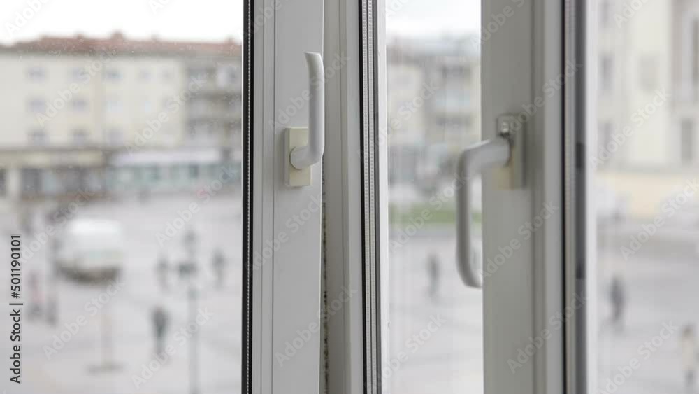 A man opens a metal-plastic window to ventilate the room. A man opens a metal-plastic window to ventilate the room.