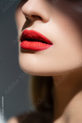 Cropped view of woman with red lips isolated on grey.