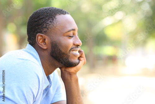 Happy man with black skin relaxing in a park