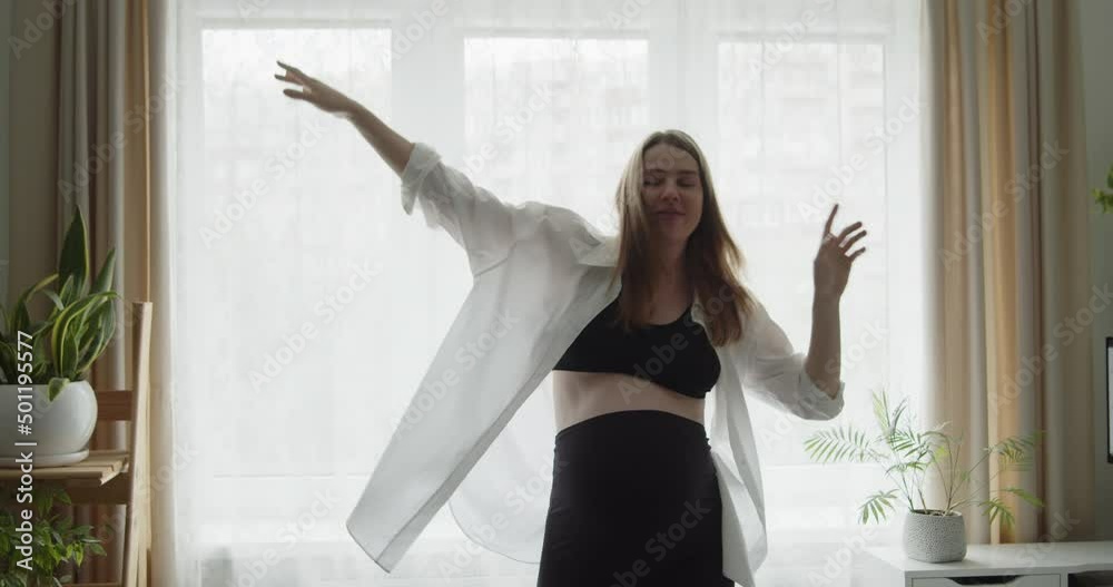 Happy cheerful pregnant young woman funny dancing near the window at home. Expectant loving mother relax at home listening to the music. Maternity prenatal care and woman pregnancy concept. Happy cheerful pregnant young woman funny dancing near the window at home. Expectant loving mother relax at home listening to the music. Maternity prenatal care and woman pregnancy concept.