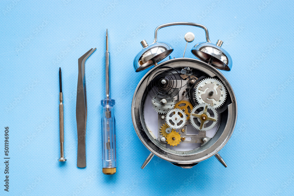 Fototapeta premium Watchmaker tools near watch mechanism of alarm clock