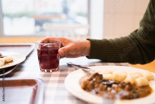 Man holding a glass of juice and eating traditional polish Gulasz at the restaurant photo