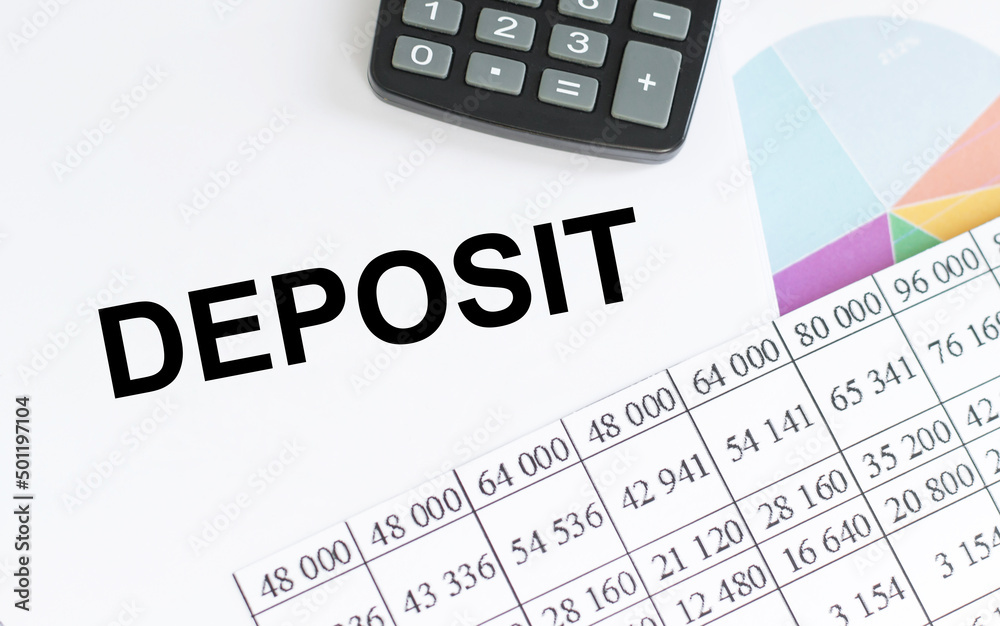 Deposit text on a notepad on the table next to the calculator and financial reports Deposit text on a notepad on the table next to the calculator and financial reports