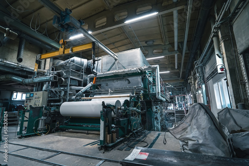 Production machine with rolls of new paper in waste paper recycling factory.