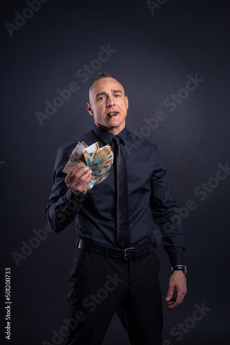 Businessman showing off money in black shirt and tie