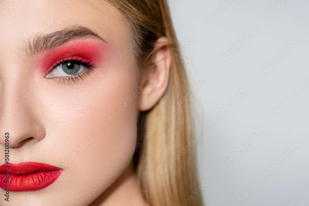 Cropped view of woman with red makeup looking at camera isolated on grey. Cropped view of woman with red makeup looking at camera isolated on grey.