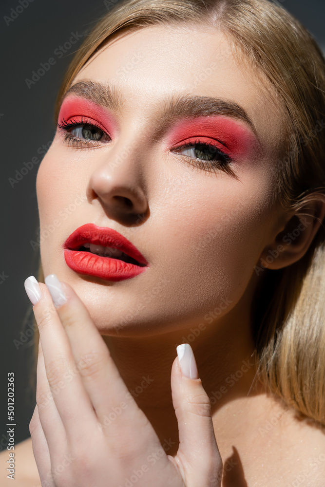 Portrait of woman with red lips touching chin isolated on grey. Portrait of woman with red lips touching chin isolated on grey.