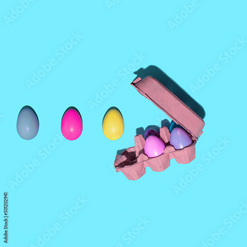 Colorful pastel eggs in carton on light blue background. Creative minimalistic Easter concept. photo