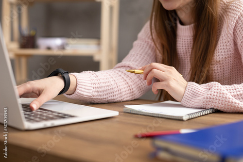 Girl speaking in headphones and writing at notebook. Student woman online larning