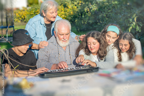 Grandfather playing outdoor with his grandchildren with music in the garden