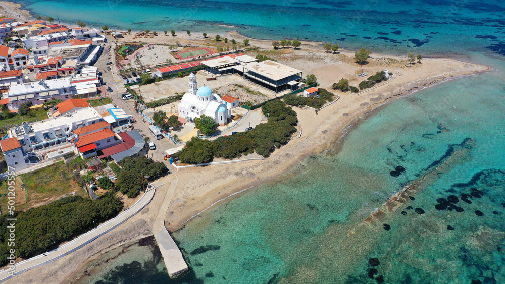 Aerial drone photo of iconic picturesque village, main port and beautiful turquoise beaches of Skala featuring landmark church of Agioi Anargiroi, Agistri island, Saronic gulf, Greece