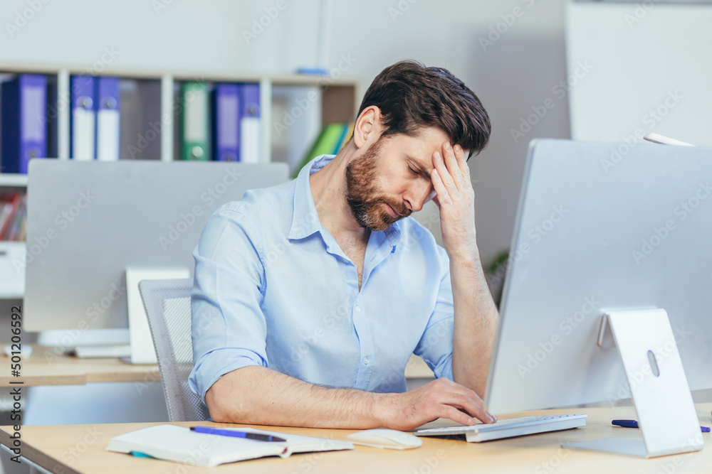 Pensive and upset man working a day in a modern office, businessman holding his hand home longing depressed Pensive and upset man working a day in a modern office, businessman holding his hand home longing depressed