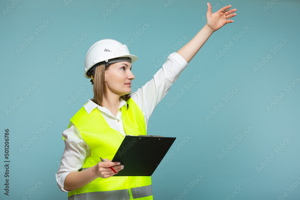 Professional engineer. A woman in a hardhat and bright jelly is using a tablet, on a blue background. Copy paste. Professional engineer. A woman in a hardhat and bright jelly is using a tablet, on a blue background. Copy paste.
