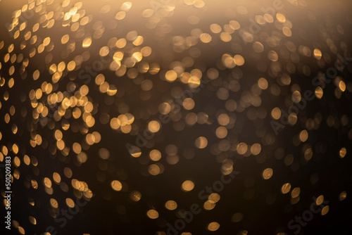 golden bokeh defocused glitter, abstract background with yellow hot bokeh on a dark background