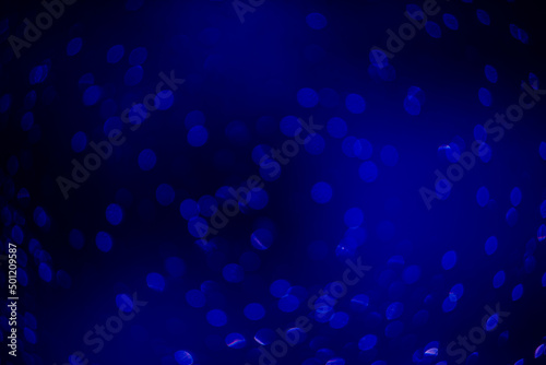 blue bokeh defocused glitter, abstract background with navy blue bokeh on a dark background © Olga Mykovych