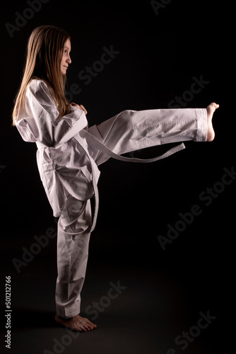 girl in kimono practicing taekwondo on black background. Sports banner. 
