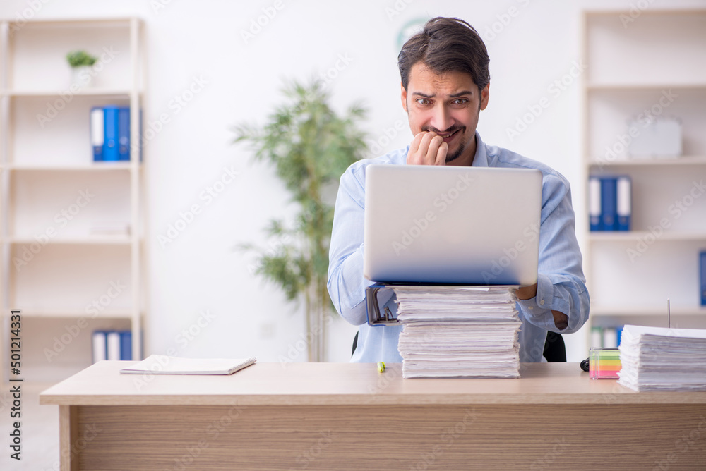 Young male employee and too much work in the office Young male employee and too much work in the office