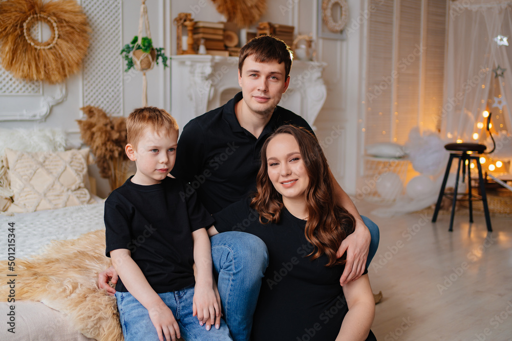 mom, dad and son in black robes on a bed in a white room. happy family. mom, dad and son in black robes on a bed in a white room. happy family.