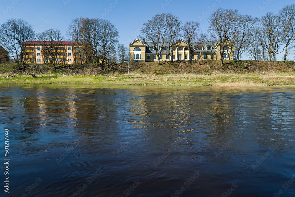 Skrunda manor and river Venta with reflection in sunny spring day, Latvia.