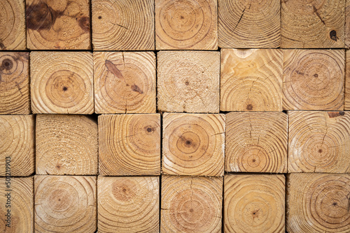 End profile view of stacked 4-inch x 4-inch wood timber, showing the rough edge and wood grain in a lumberyard photo