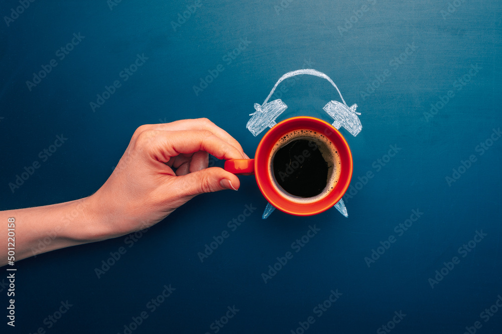 Coffee cup top view with manual alarm clock on a chalkboard background. Break time, good morning, drinks menu design concept. Hand holding cup of coffee Coffee cup top view with manual alarm clock on a chalkboard background. Break time, good morning, drinks menu design concept. Hand holding cup of coffee