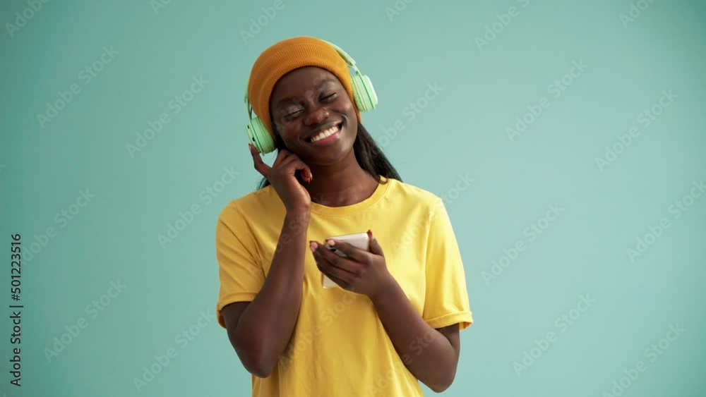 Pretty African woman wearing headphones dancing in the turquoise studio Pretty African woman wearing headphones dancing in the turquoise studio