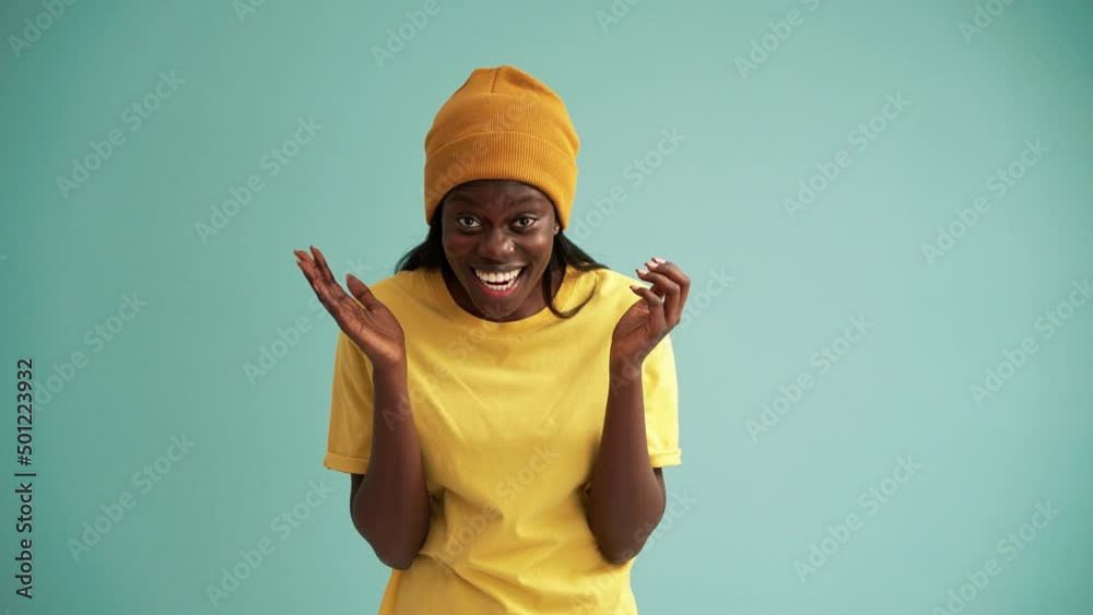 Shocked African woman rejoicing at the camera in the turquoise studio Shocked African woman rejoicing at the camera in the turquoise studio
