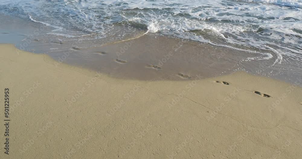 Women footsteps washed away by ocean waves in the sand on tropical beach. Women footsteps washed away by ocean waves in the sand on tropical beach.