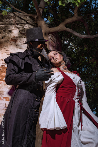 Black plague doctor with a nearly dead medieval lady